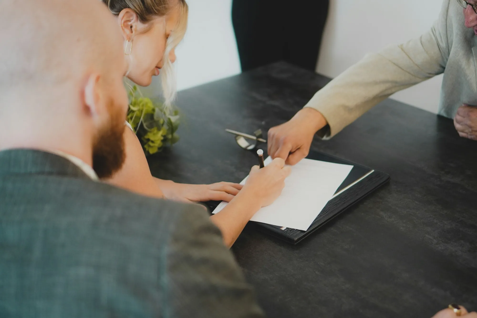Two people reviewing and signing papers across a dark table