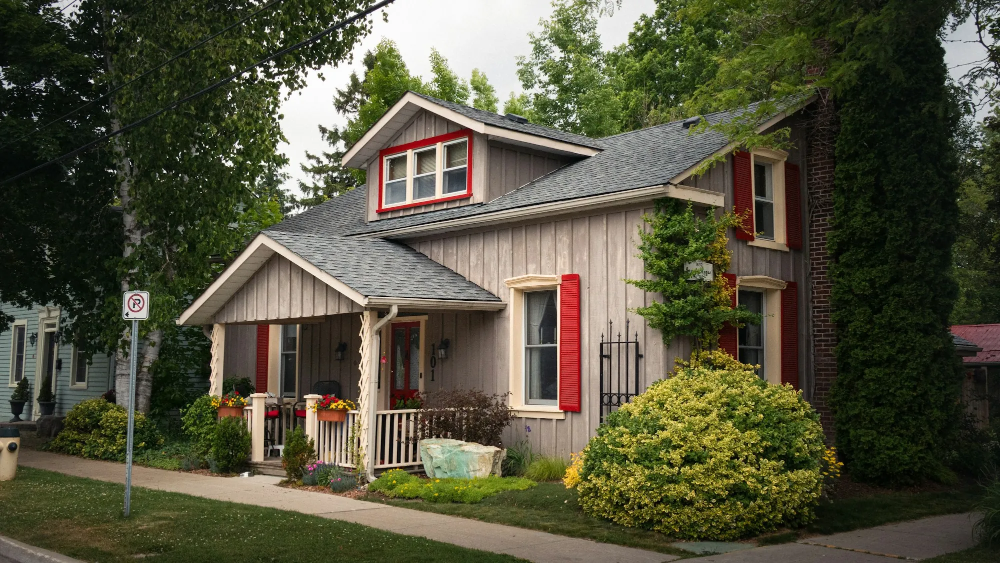 Craftsman cottage with a gray shingle roof and red trim