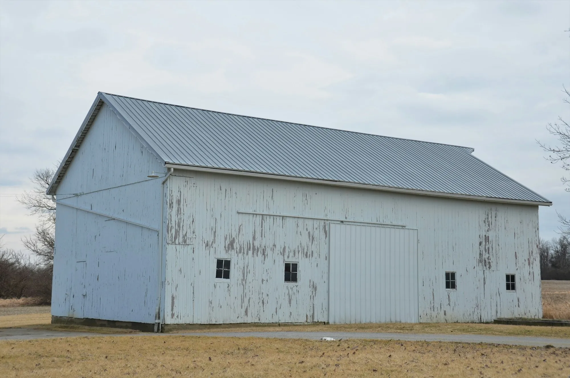 White barn with a long metal roof in an open field