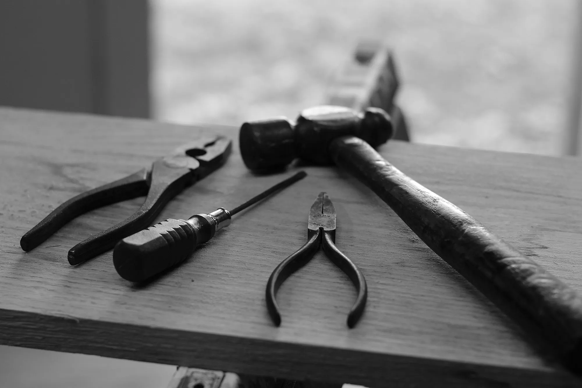 Hammer, pliers and screwdriver on a wooden plank